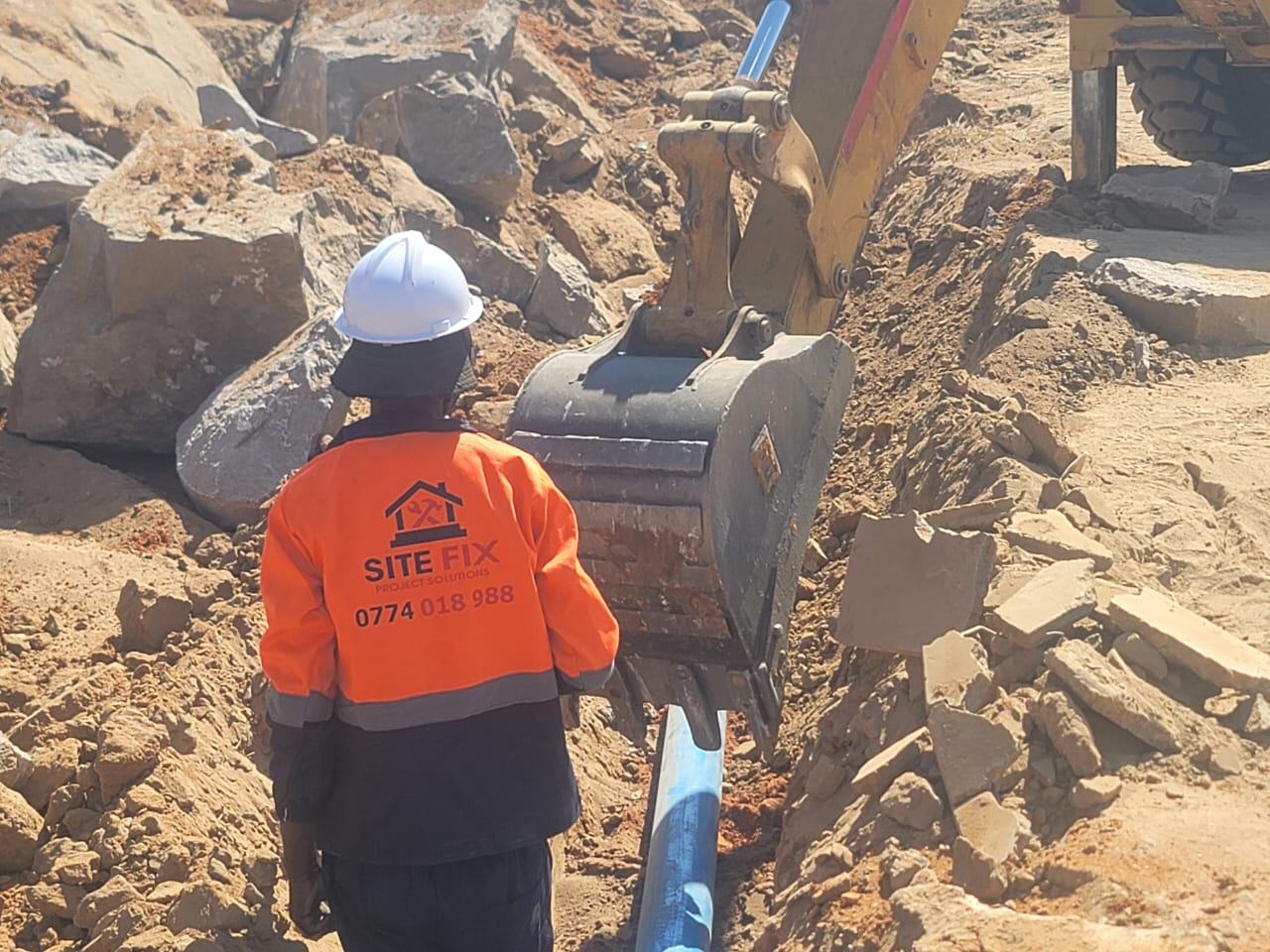 Excavator bucket cutting into a trench on an active SiteFix job site
